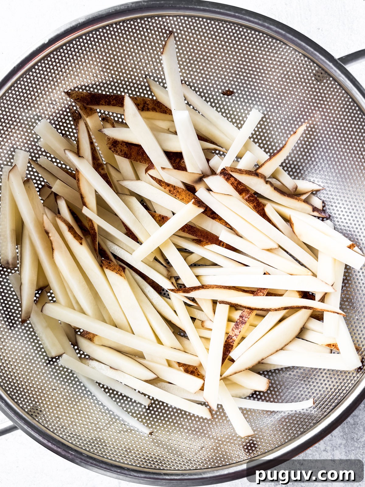 Crispy Air Fryer French Fries with 3 Ingredients 8 Uncooked fries in a colander.