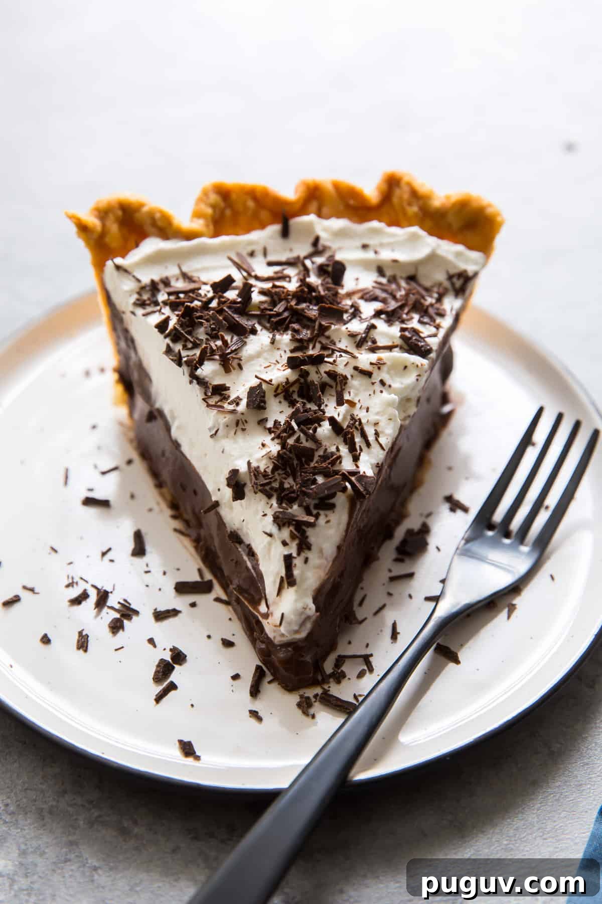 A close up of a slice of pie on a white plate with a fork.