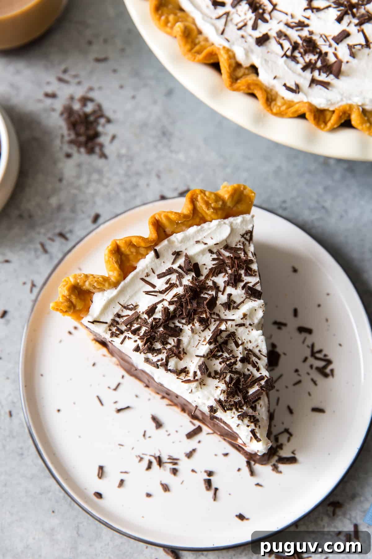 A slice of chocolate pie topped with whipped cream and chocolate shavings shot from over the top.