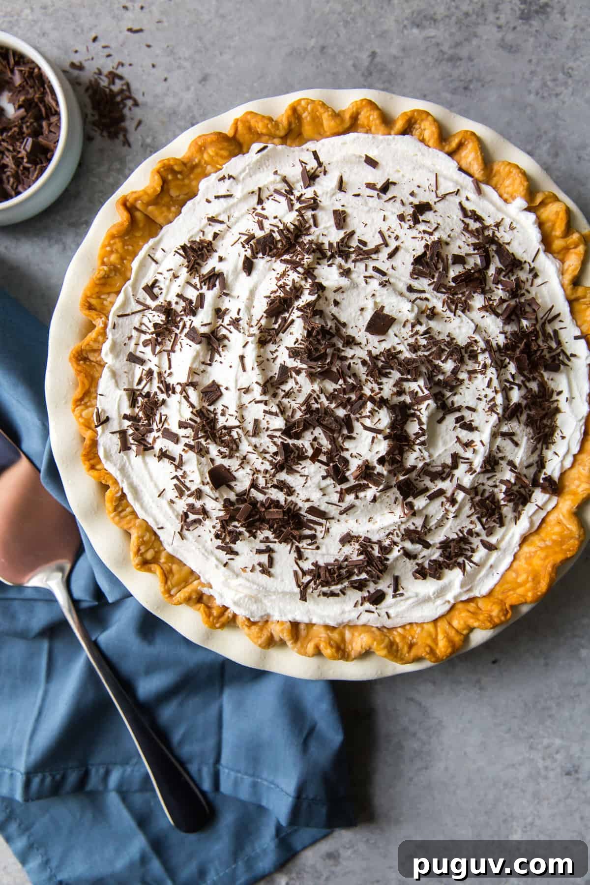 A pie topped with whipped cream and shaved chocolate shot from over the top.