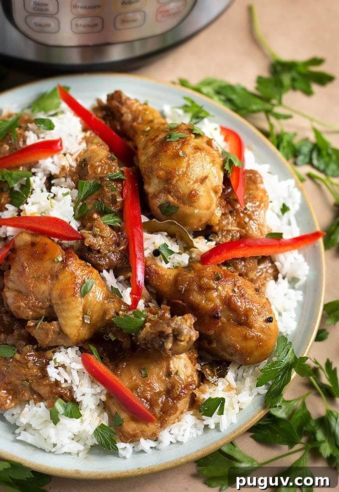 Instant Pot Filipino Chicken Adobo — Quick Authentic Recipe 2 Chicken Adobo Filipino with rice on a white plate garnished with red peppers, cilantro