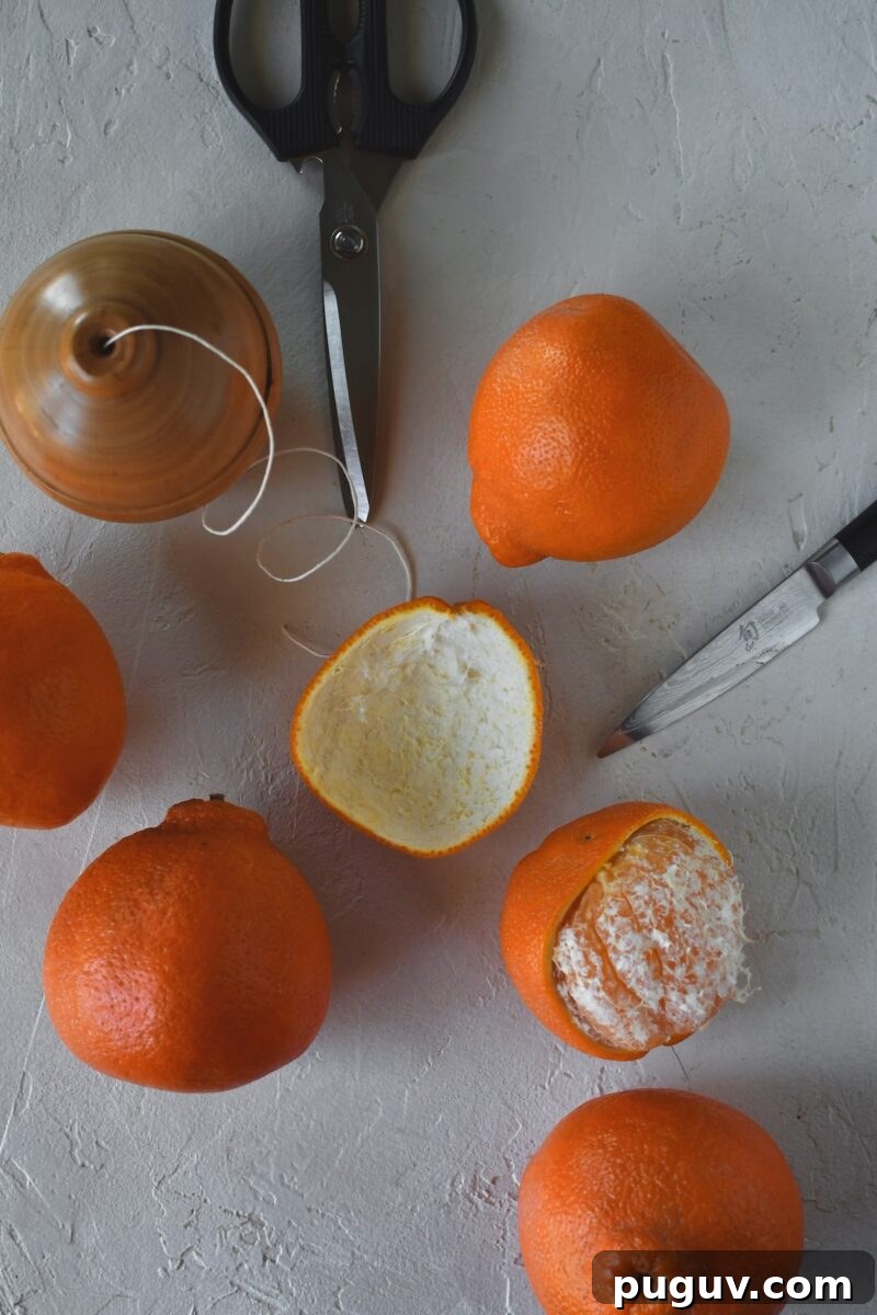 DIY Orange Peel Star Garland: Natural Holiday Decoration Tutorial 4 Oranges on a table, one has had its peel removed in one large piece.