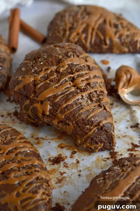 Gingerbread scones on parchment paper with a spoonful of Biscoff spread on the side