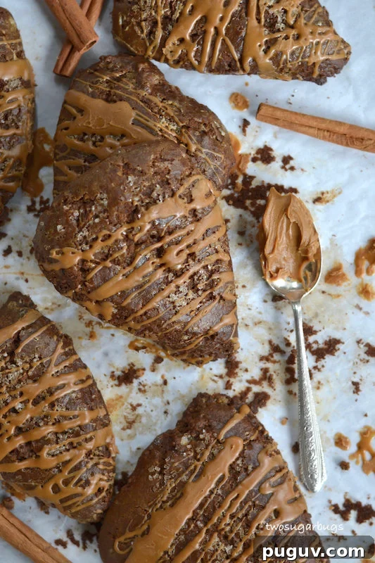 a pile of gingerbread scones on parchment paper with a spoonful of Biscoff spread