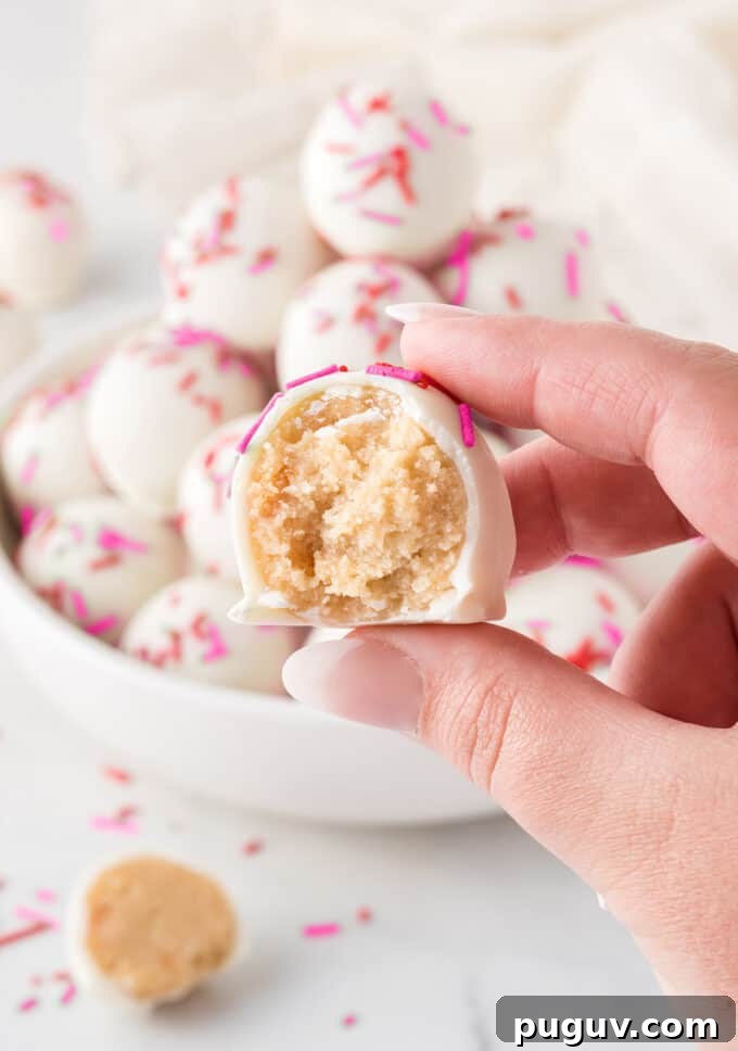Valentine Sugar Cookie Truffles: Creamy Heart-Shaped Dessert Bites 4 hand holding sugar cookie Valentine truffle with bite