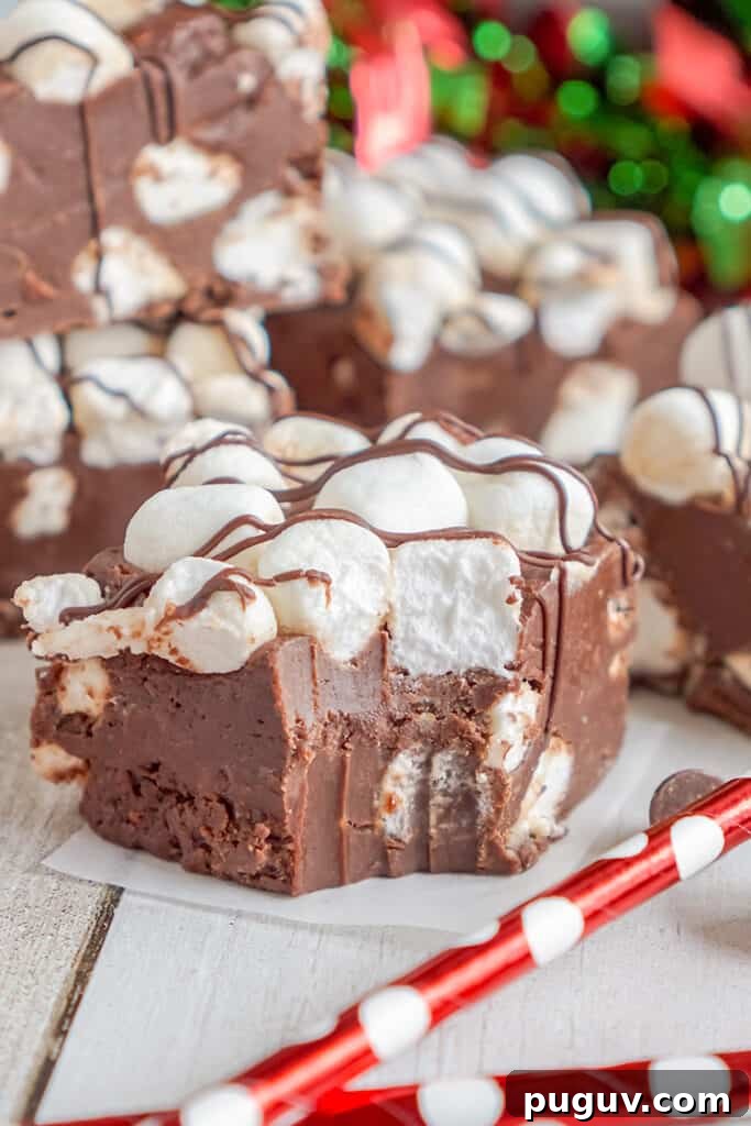 Decadent Hot Chocolate Fudge Recipe for Rich Cocoa Lovers 10 fudge on a piece of wax paper with red straws in front of it and a bite taken out of the fudge
