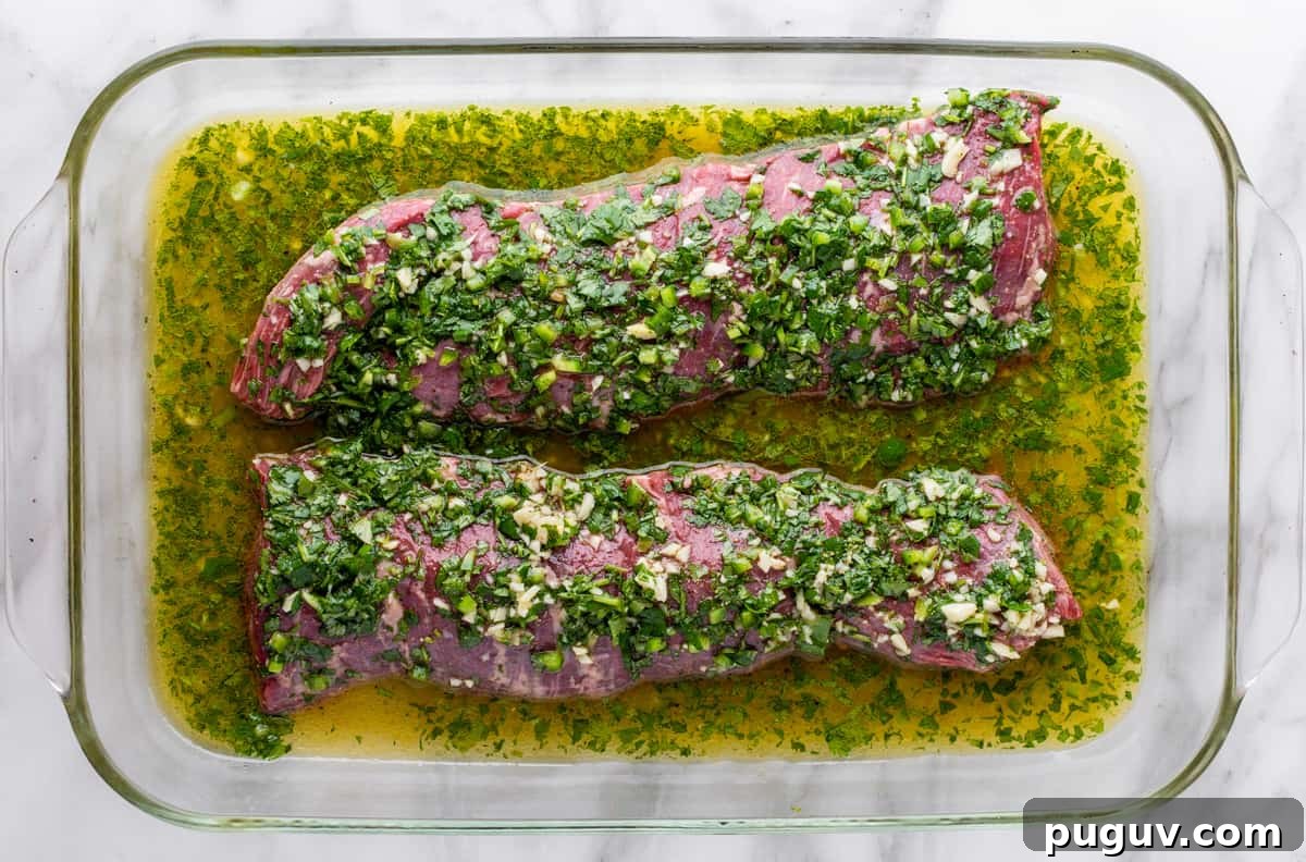 raw skirt steak in carne asada marinade in glass baking dish.
