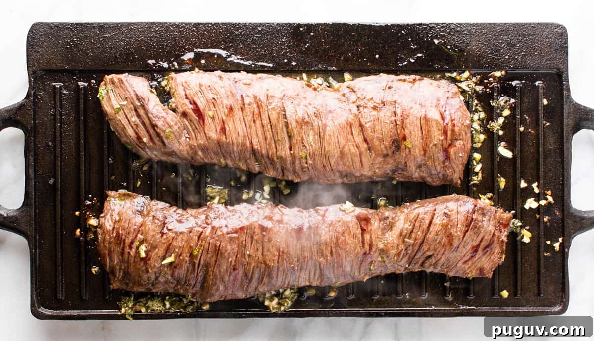cooked carne asada steak on grill pan with steam rising.