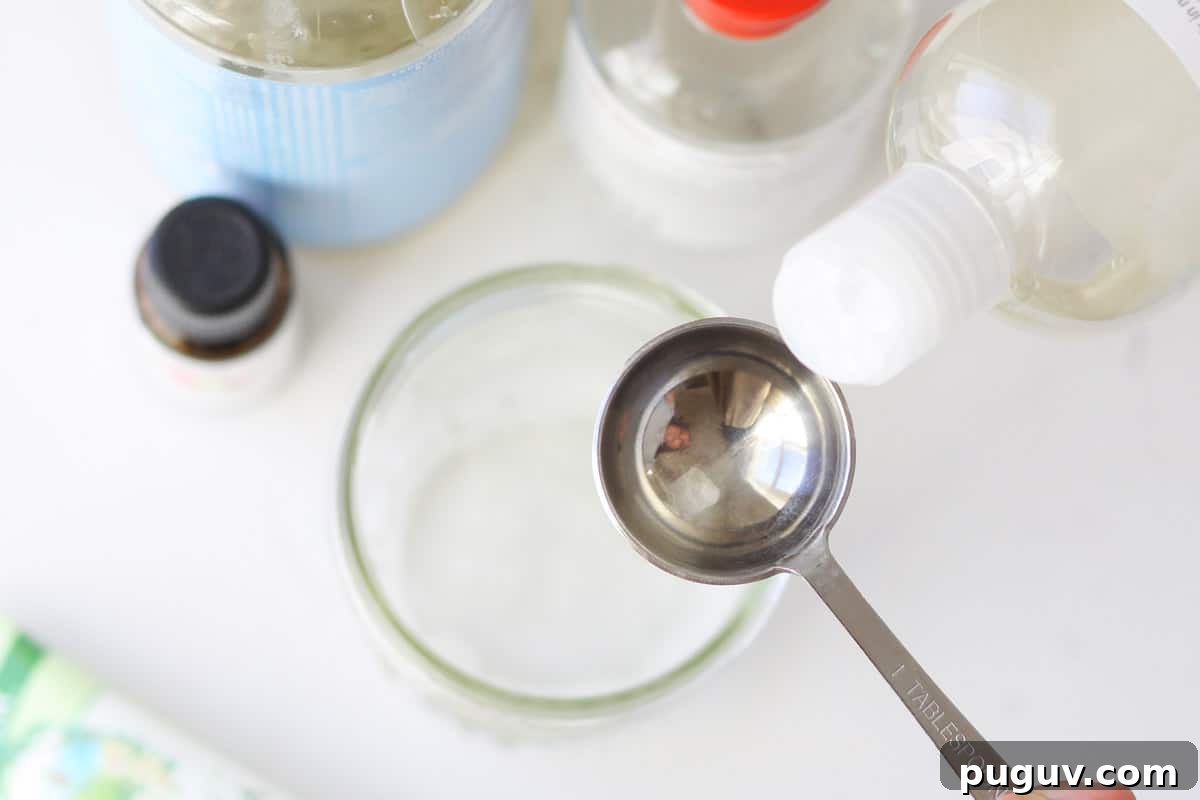 Make Your Own Coconut Oil Makeup Remover Wipes at Home 5 castile soap and fractioned coconut oil being poured into a tablespoon over a mason jar