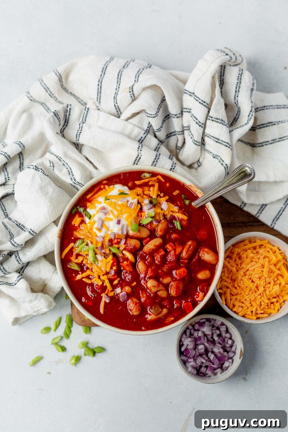 Smoky White Bean Vegetarian Chili — Slow Cooker Recipe 5 slow cooker vegetarian chili in a white bowl with shredded cheese and onion next to it