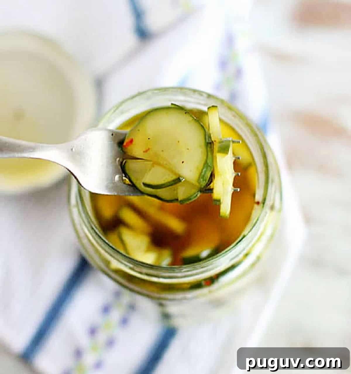 Quick Refrigerator Pickled Cucumbers: Tangy Crunch in 24 Hours 2 Top view of fork with pickled cucumbers over jar and kitchen towel
