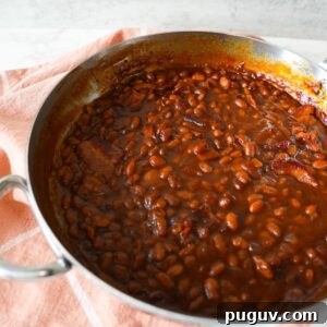 Classic Oven-Baked Beans Recipe with Step-by-Step Video 12 Baked beans with crispy bacon in a skillet, served warm and bubbly straight from the oven.