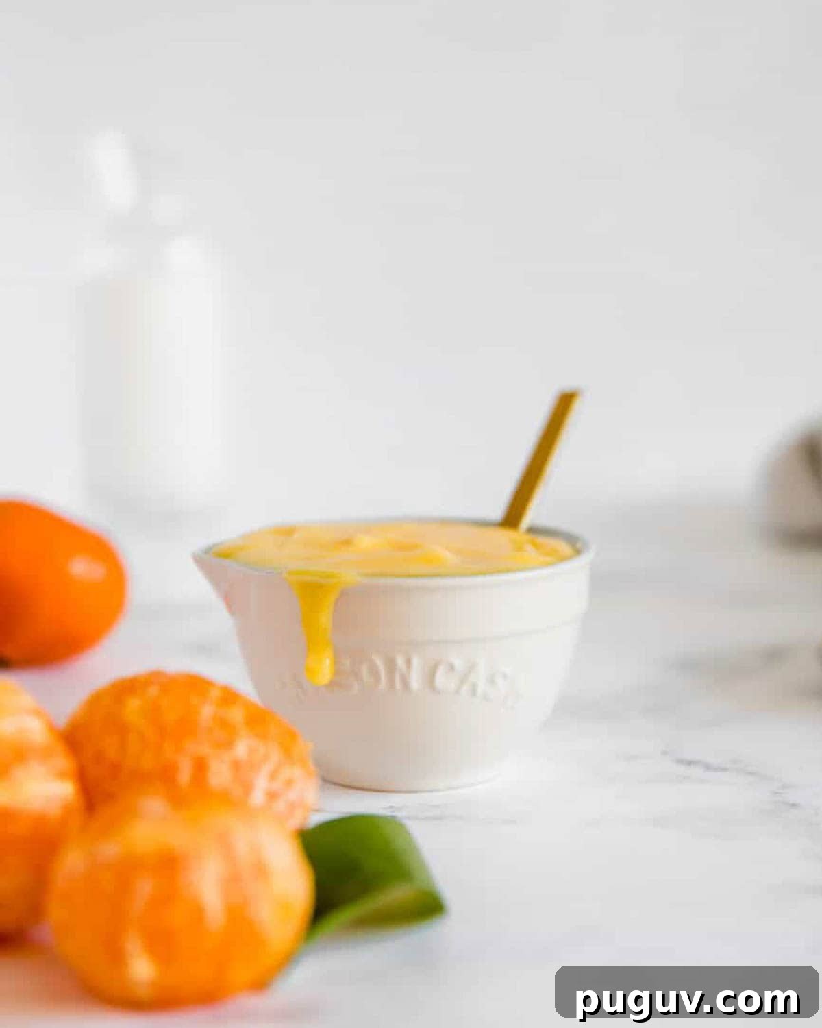 A bowl of clementine curd sitting on a marble counter.