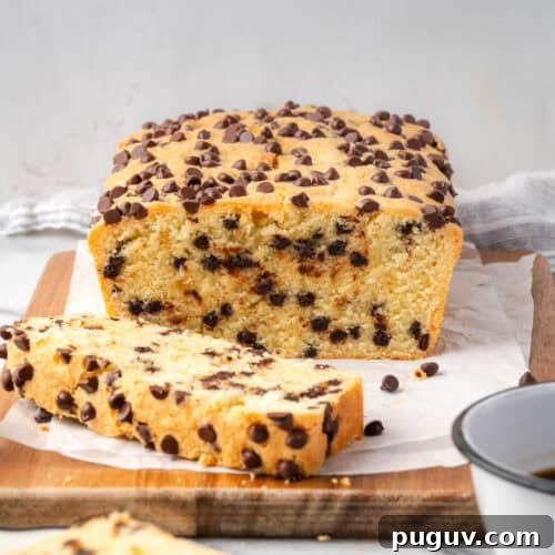 A loaf of chocolate chip pound cake cut into slices and sitting on a wood cutting board.