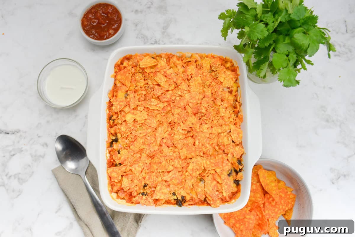 Doritos Casserole Recipe with WW SmartPoints and Tips 13 A white square baking dish is shown with the now cooked casserole. To the side are a serving spoon, bunch of cilantro and bowls filled with Doritos, Greek Yogurt and salsa.