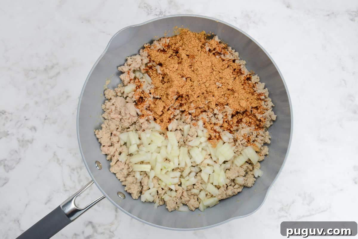Doritos Casserole Recipe with WW SmartPoints and Tips 4 A skillet with cooked light brown ground chicken, taco seasoning and diced onions.