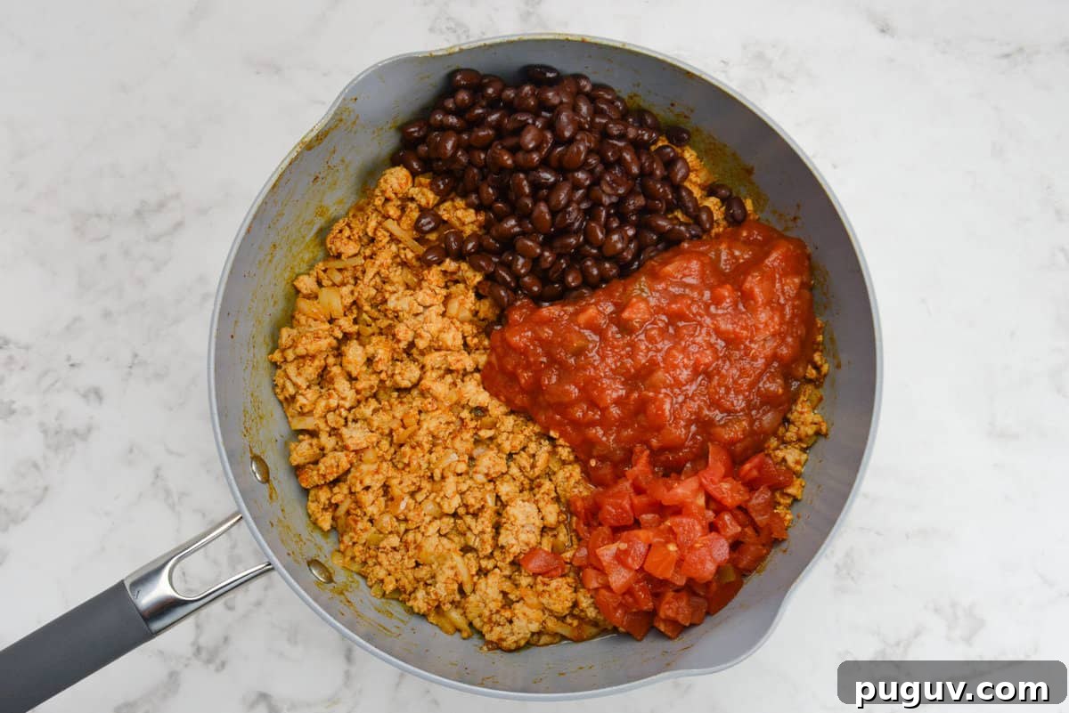 Doritos Casserole Recipe with WW SmartPoints and Tips 6 A skillet with ground chicken, black beans, salsa, and diced tomatoes that are not mixed together.