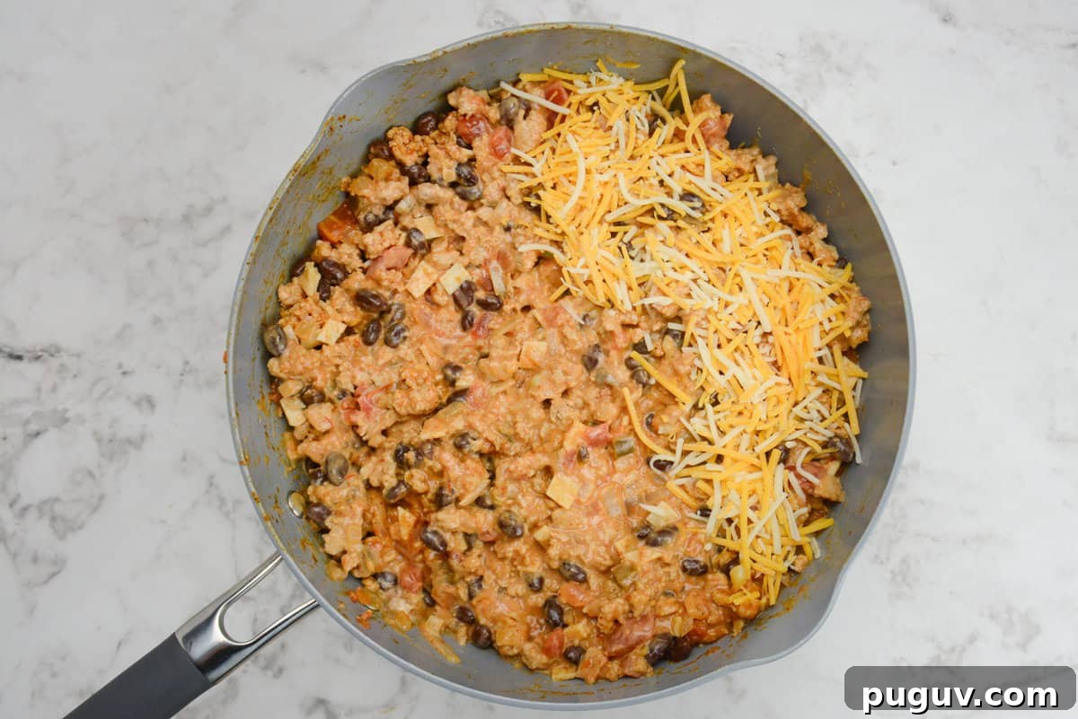 Doritos Casserole Recipe with WW SmartPoints and Tips 9 A skillet is shown with the casserole ingredients mixed well with a portion of orange and white cheese on top.