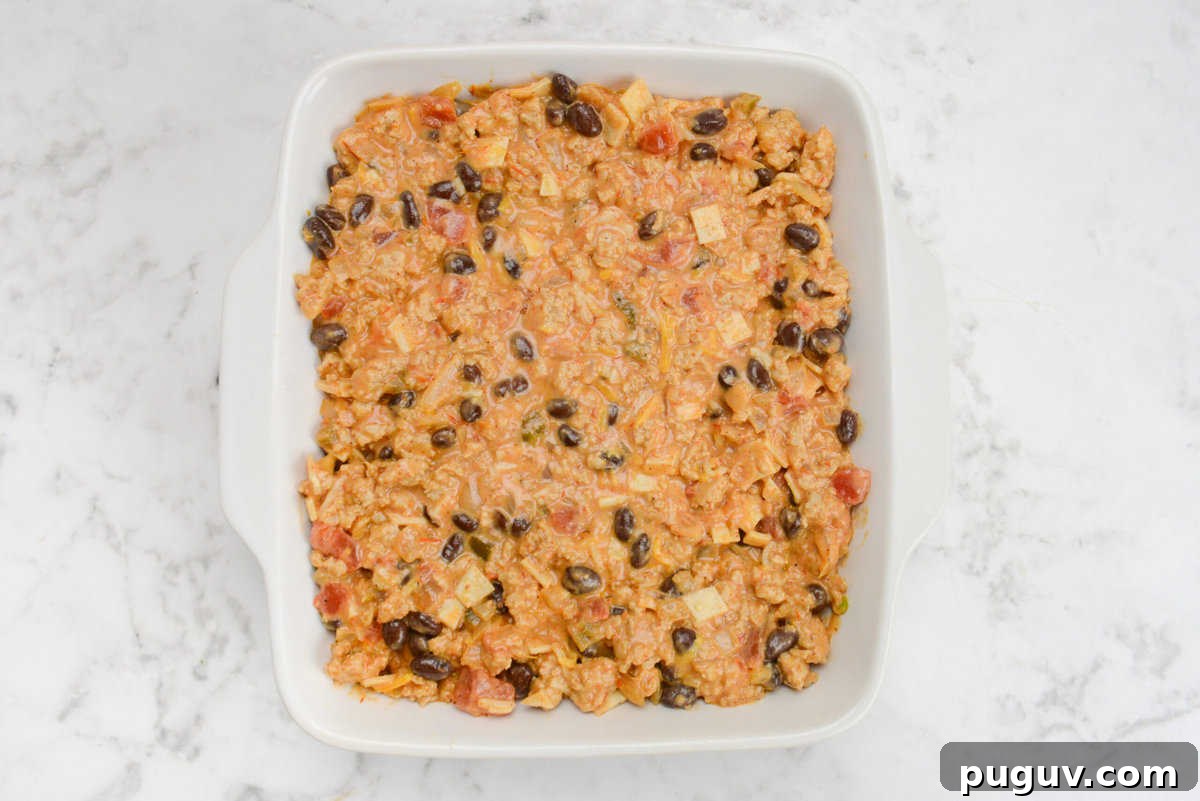 Doritos Casserole Recipe with WW SmartPoints and Tips 10 A white square baking dish filled with the casserole mixture is on a white marble surface.