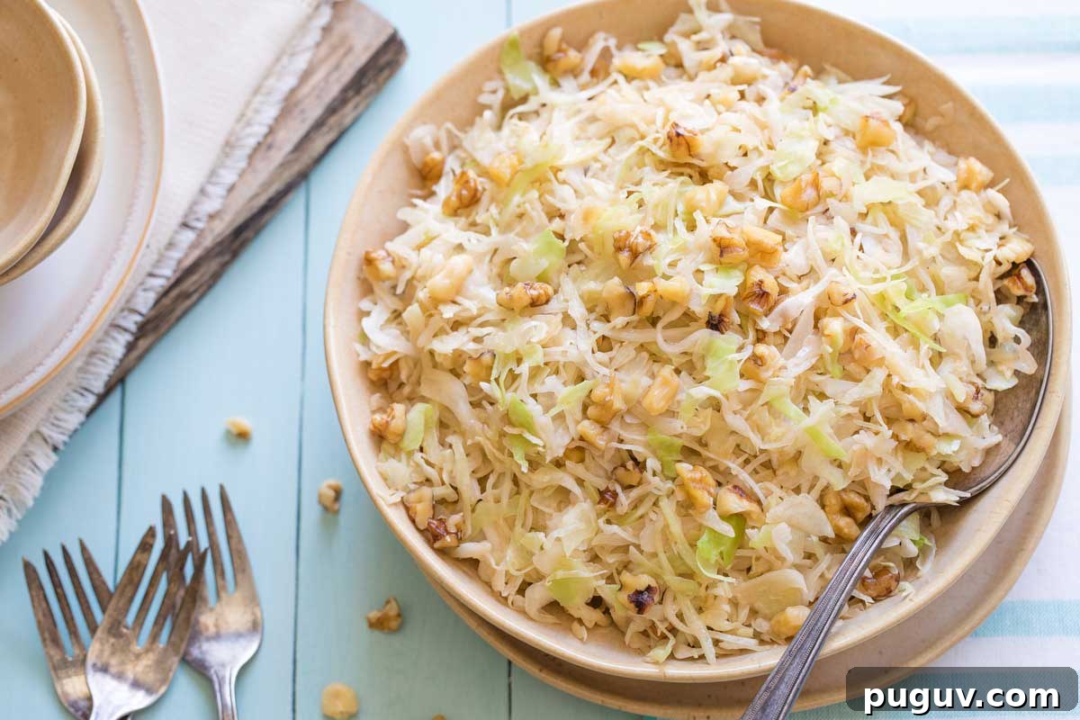 Brown Butter Sautéed Cabbage with Toasted Walnuts 3 Tan serving set on blue background, piled with sauteed cabbage with spoon tucked in and forks and plates nearby.