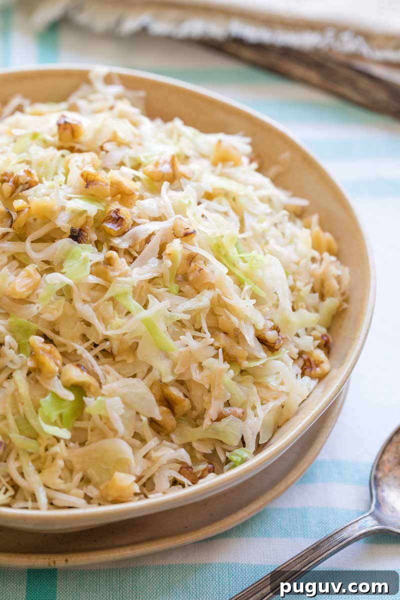 Brown Butter Sautéed Cabbage with Toasted Walnuts 5 Side view of right half of serving bowl filled with the cooked cabbage, with antique serving spoon at side.