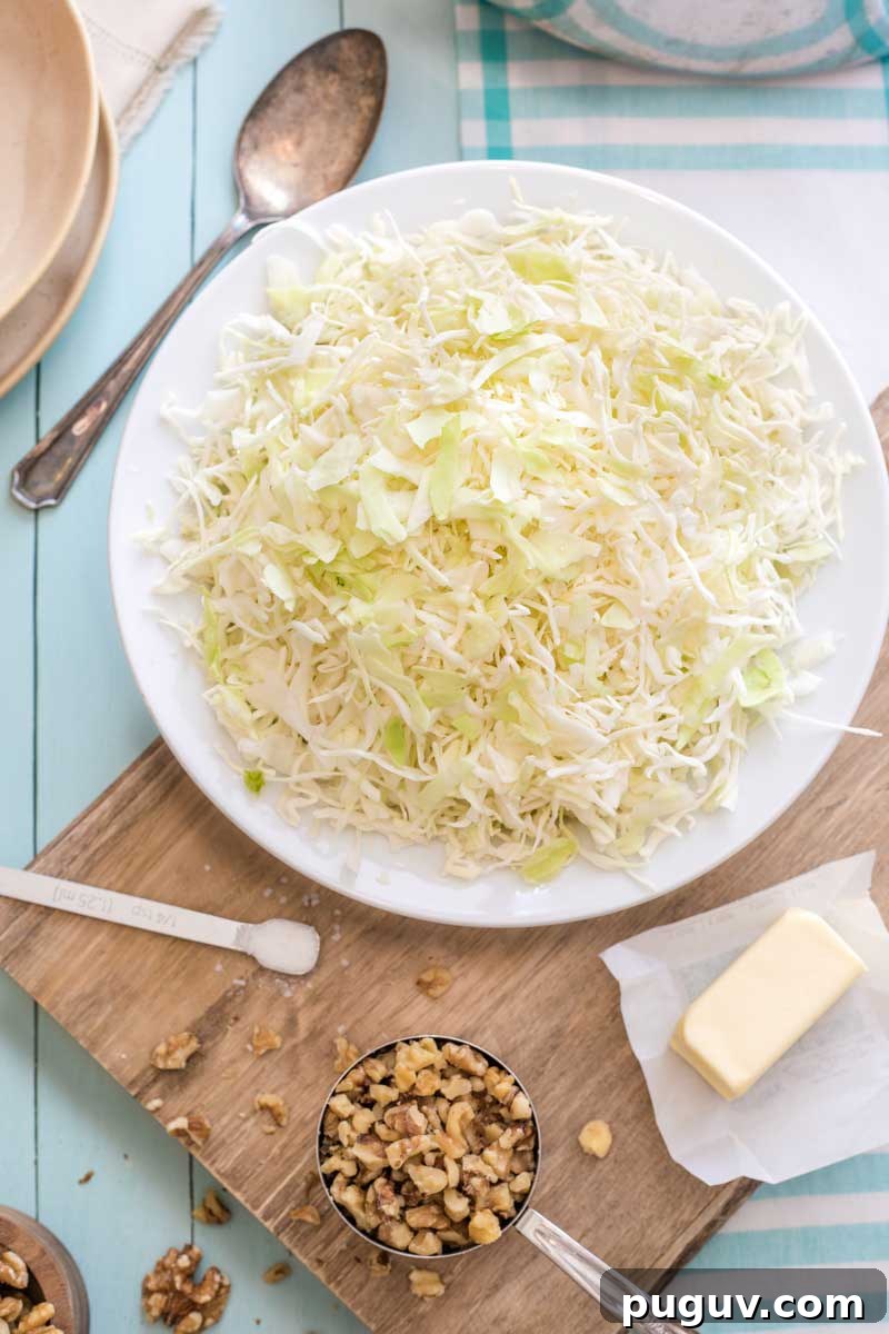 Brown Butter Sautéed Cabbage with Toasted Walnuts 6 Overhead of shredded, raw cabbage, stick butter, chopped nuts and salt on cutting board, ready for cooking.