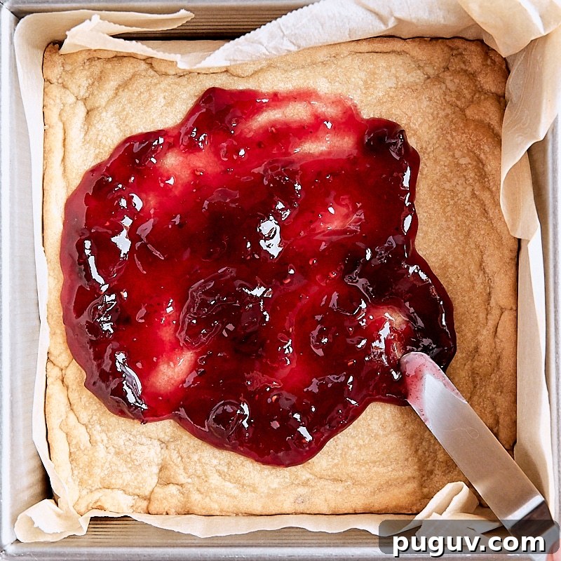 Homemade Jam Crumble Bars Recipe — Simple Fruit-Filled Dessert 4 Jam filling added to crumb bars with an offset spatula