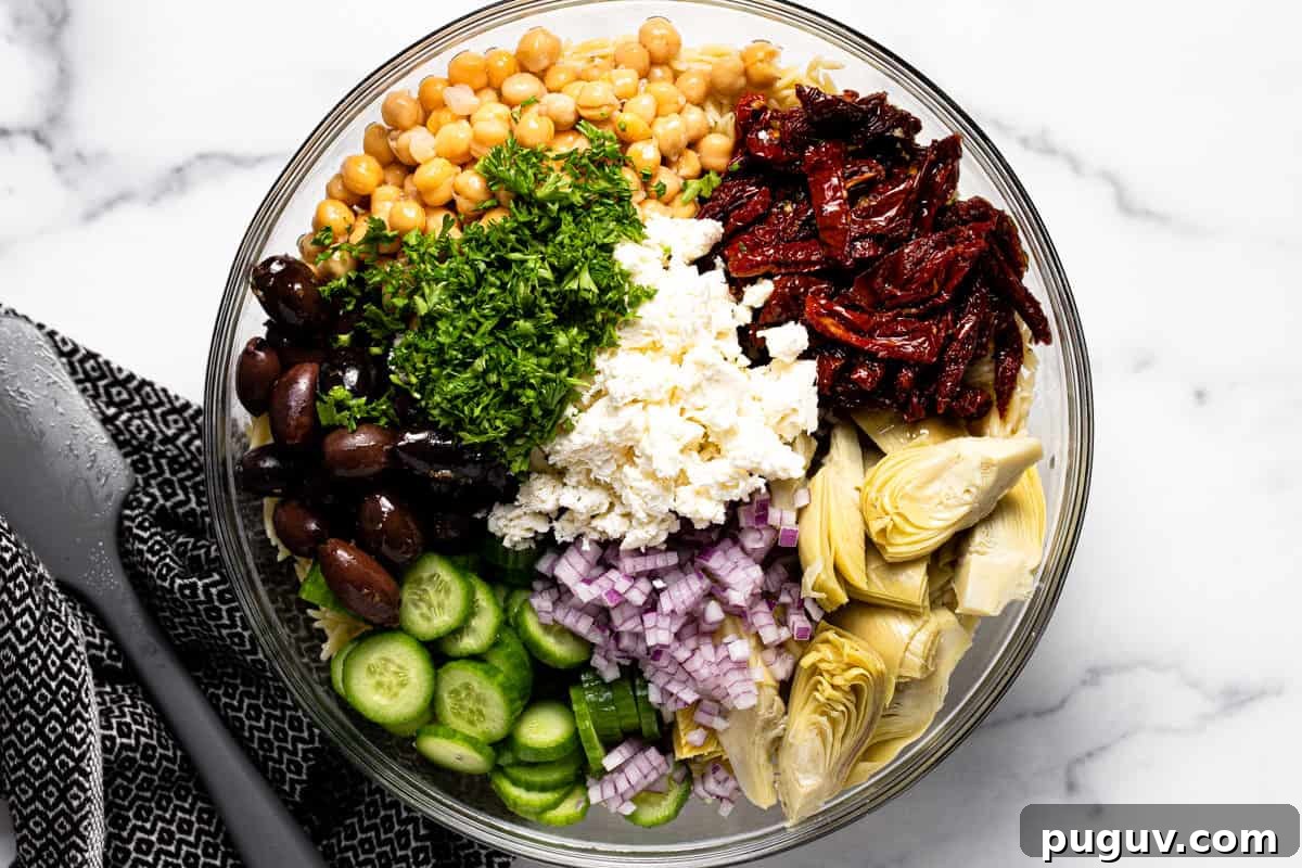 20-Minute Greek Orzo Salad with Feta & Olives 5 Glass bowl filled with ingredients to make Mediterranean pasta salad