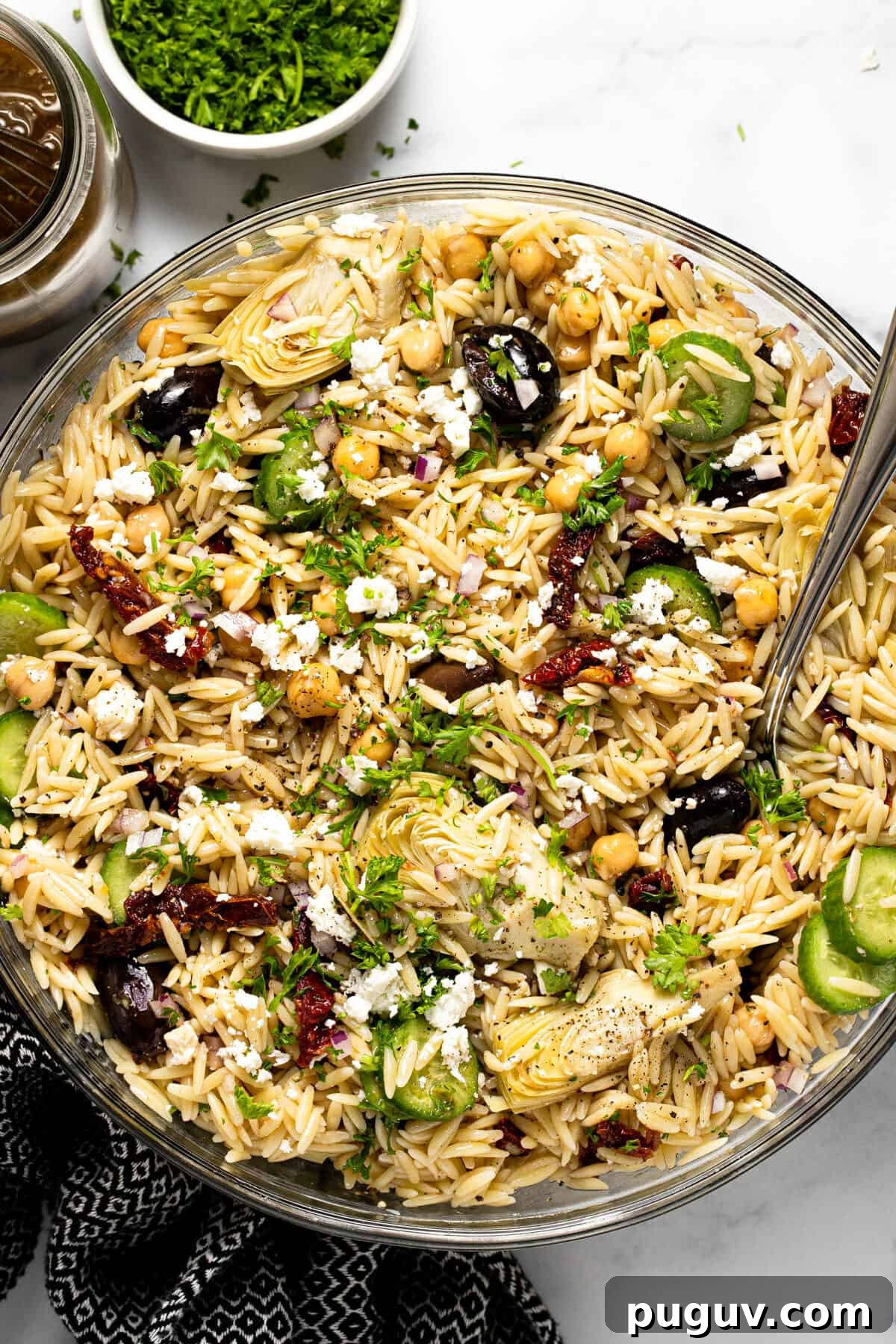20-Minute Greek Orzo Salad with Feta & Olives 7 Large glass bowl filled with Greek pasta salad garnished with parsley
