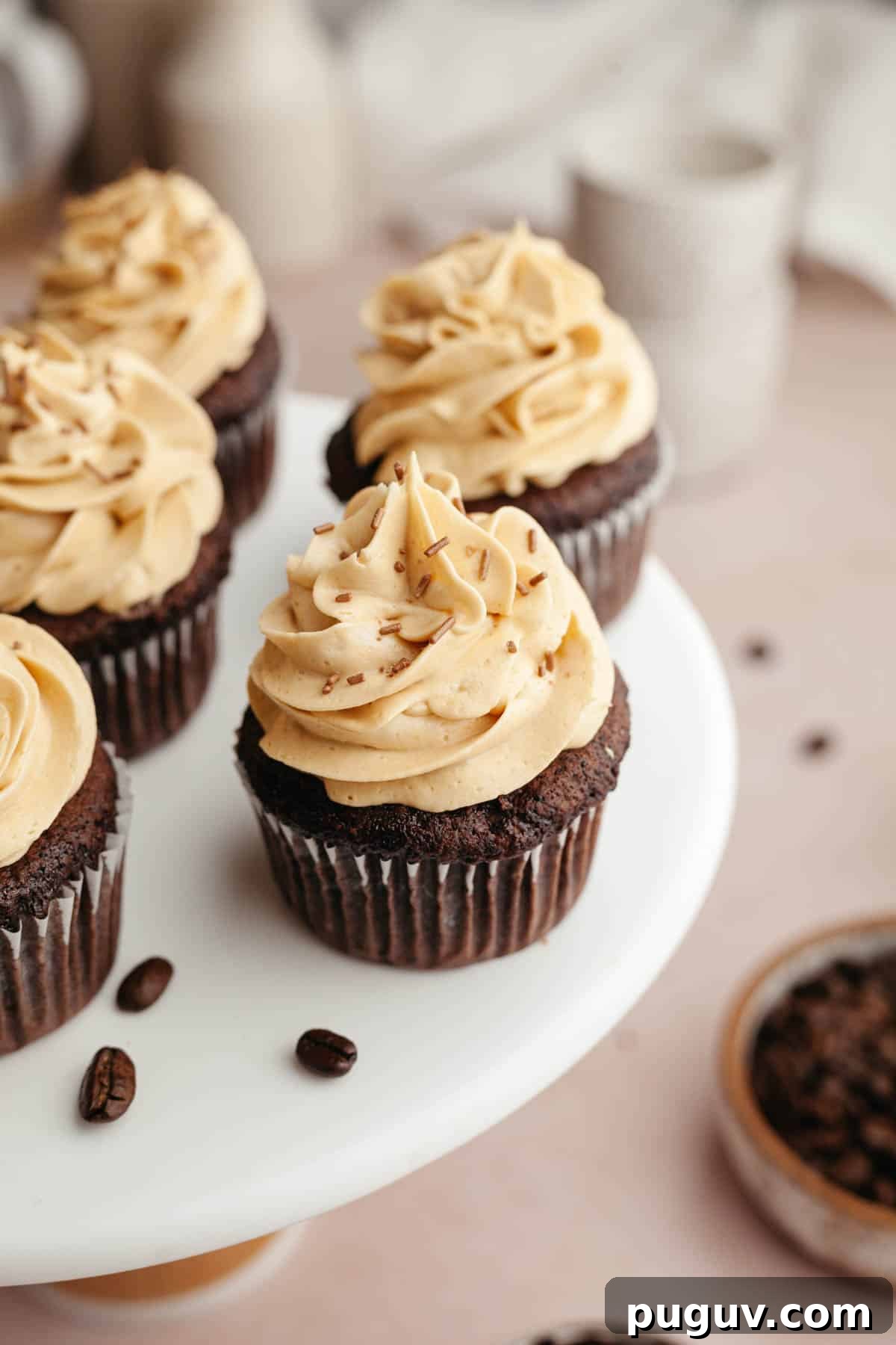 Chocolate cupcakes with coffee frosting on a white cake stand.