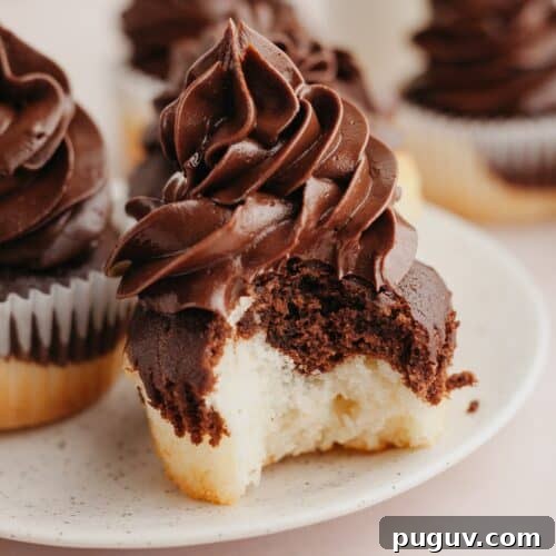 A close up of a marbled cupcake with chocolate frosting, a bite has been taken out of the cupcake.
