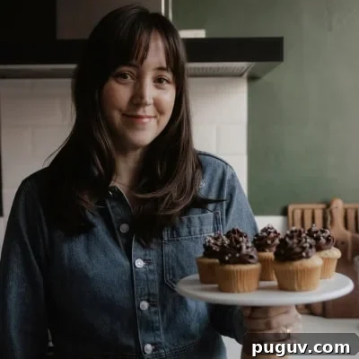 Ella from Alpine Ella is holding a cake stand with cupcakes on it.