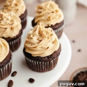 Chocolate cupcakes with coffee frosting on a white cake stand.