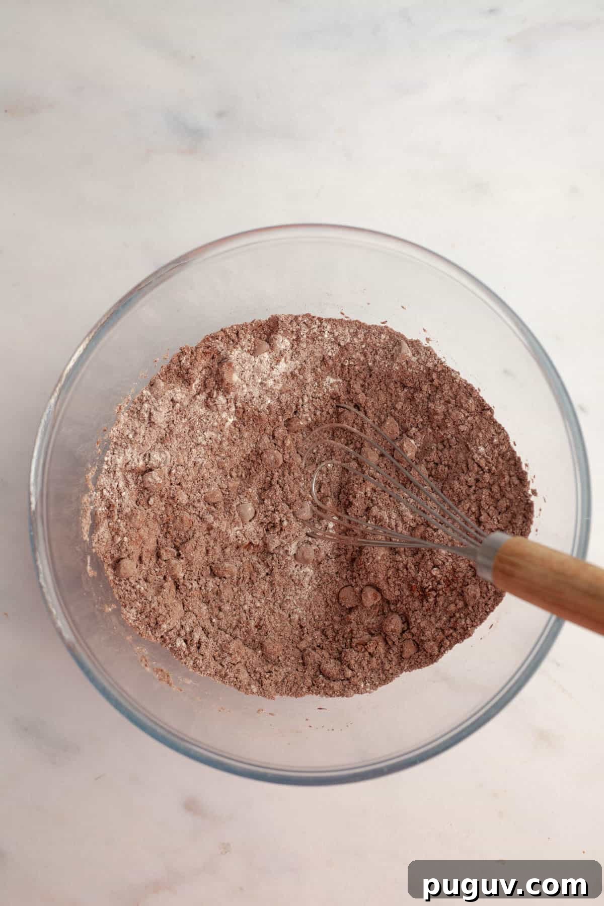 A glass bowl with cocoa powder, flour and chocolate chips.