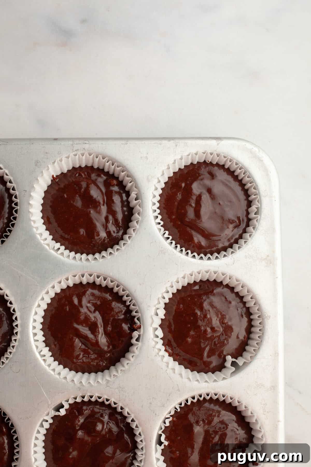 Unbaked chocolate cupcakes in a cupcake pan.