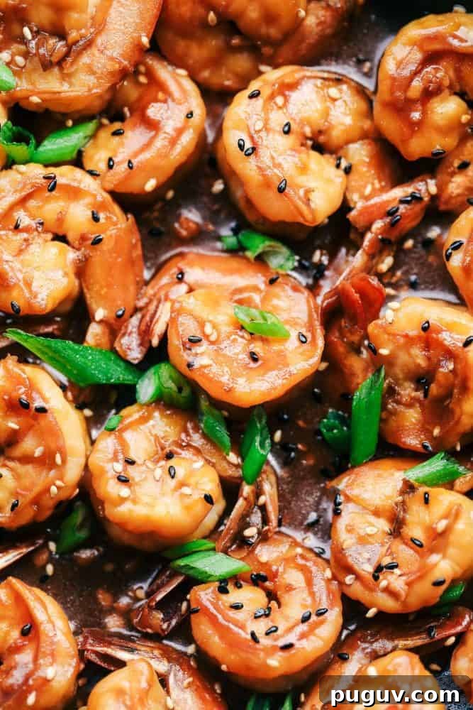 Sticky Sesame Garlic Shrimp is coated in the most amazing sticky Asian sauce and topped with green onions and sesame seeds! This is a quick and easy 30-minute meal that you will make again and again! Close up of Sticky Sesame Garlic Shrimp