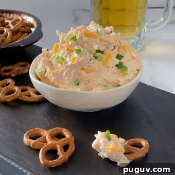 beer cheddar cheese dip with pretzels on a cutting board.