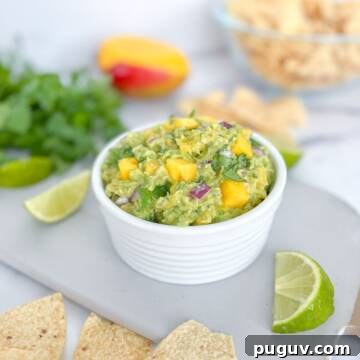 Mango guacamole with lime wedges and tortilla chips.
