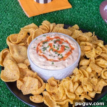 Buffalo onion dip with fritos corn chips around it.