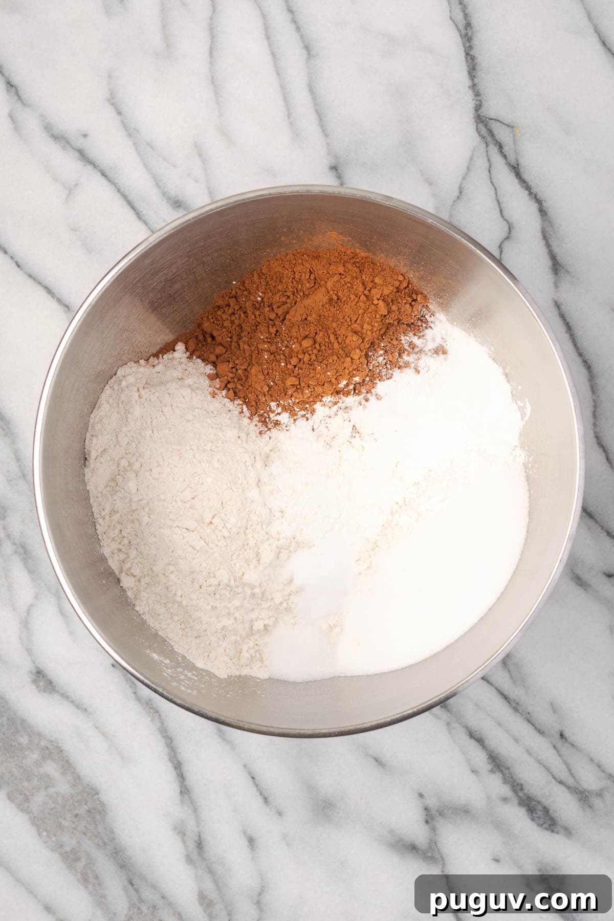 Decadent Chocolate Coconut Cake Recipe (Moist & Easy to Make) 4 Flour, sugar, cocoa powder, cornstarch, baking powder, baking soda, and salt combined in a large metal mixing bowl.