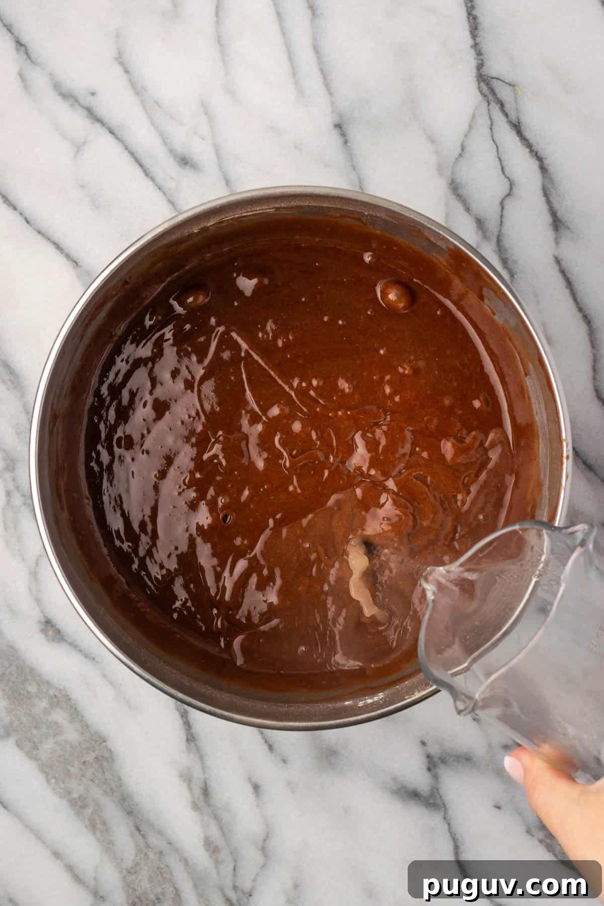 Decadent Chocolate Coconut Cake Recipe (Moist & Easy to Make) 6 Hot water being poured into the bowl with the chocolate cake batter.
