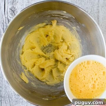 Cream butter in the bottom of a stainless steel bowl with beaten egg being poured in.