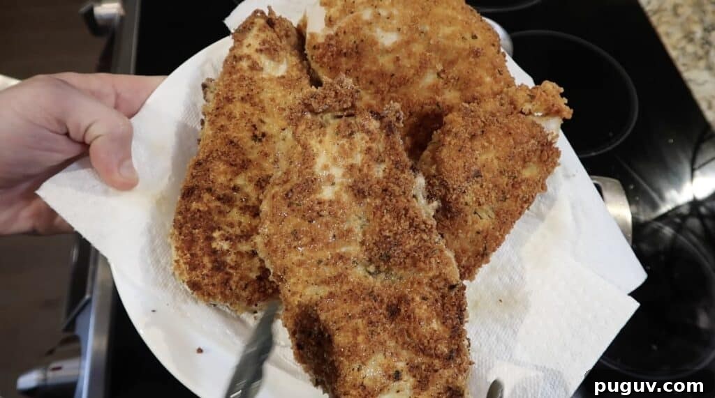 Golden-brown pan-fried chicken cutlets on a paper towel-lined plate