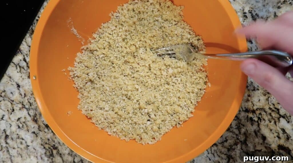 Mixing breadcrumbs and oil together with a fork.