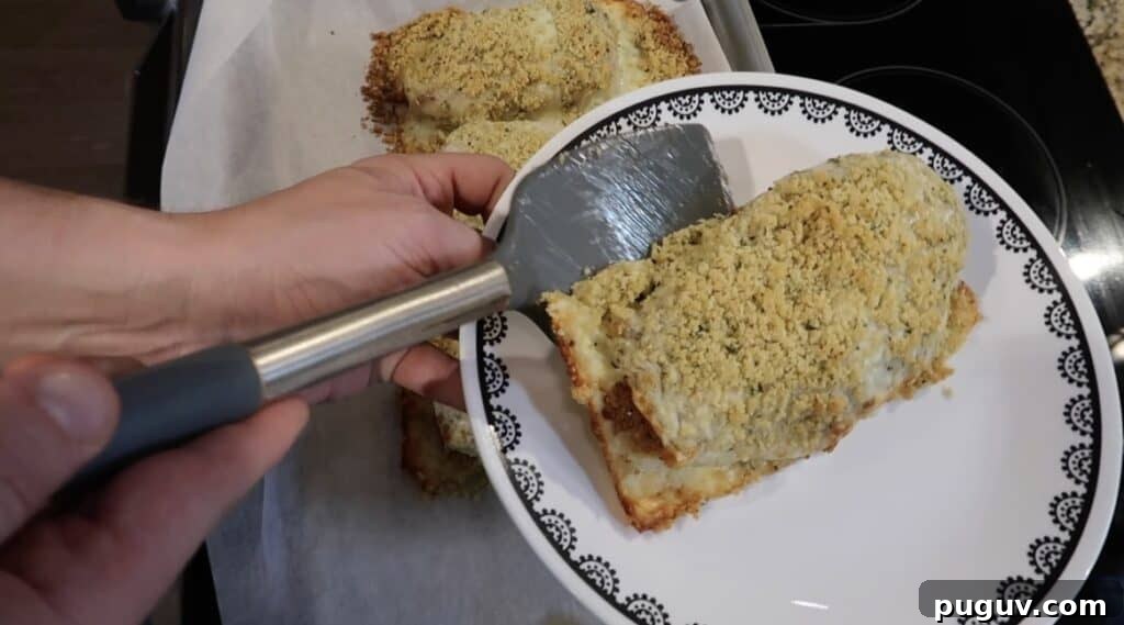 Spatula transferring the chicken cutlet to a plate