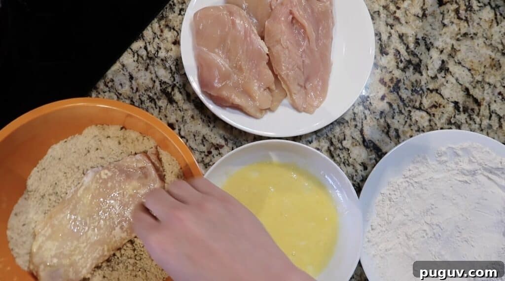 Egg and flour-coated cutlet is being coated in the breadcrumbs.