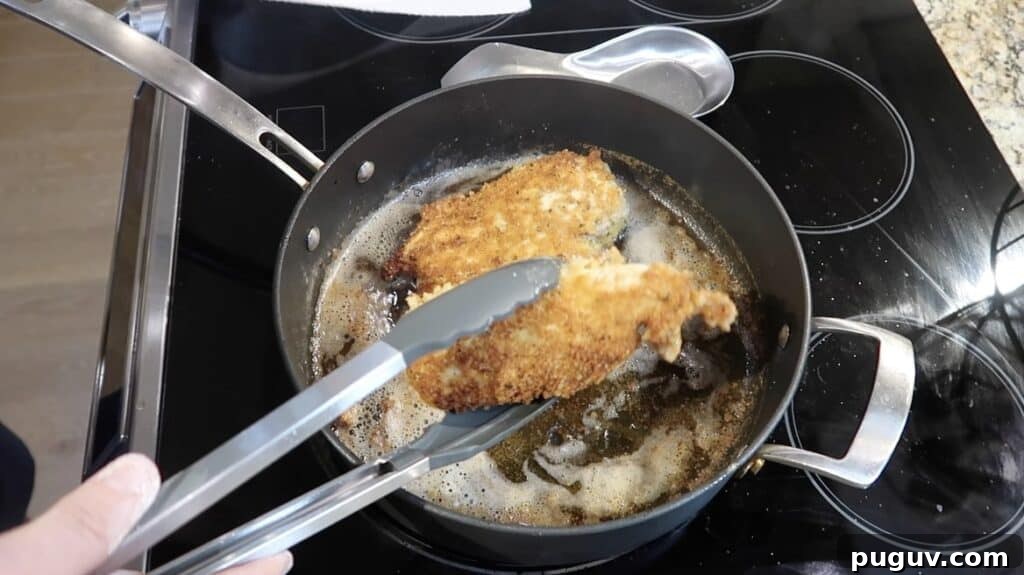 Flipping the cutlets in the pan to reveal a golden-brown crust