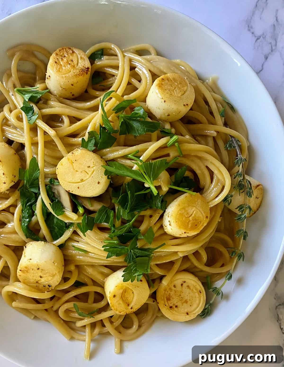 Crispy Vegan Scallops Recipe with Garlic Lemon Butter Sauce 2 vegan scallops in a bowl served on top of creamy garlic pasta and garnished with parsley.