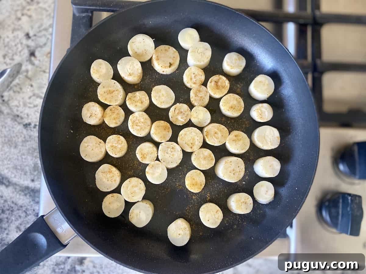 Crispy Vegan Scallops Recipe with Garlic Lemon Butter Sauce 7 Hearts of palm scallops cooking in a skillet in a pan.