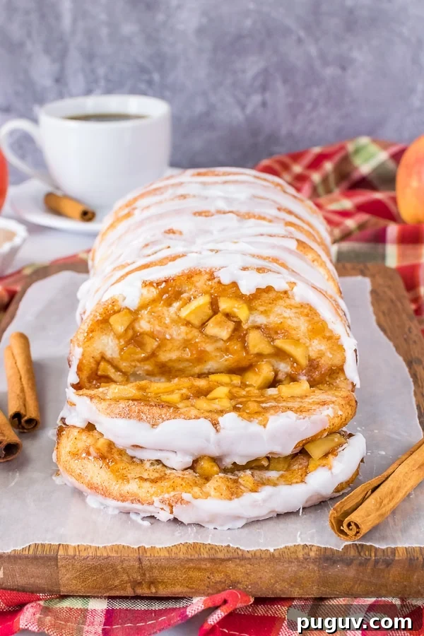 Apple Cinnamon Pull Apart Bread - homemade bread dough filled with homemade apple pie filling bakes into a delicious and gooey pull apart bread. Make this homemade recipe for breakfast or brunch this fall. A loaf of apple cinnamon pull apart bread with two slices of the bread lying down showing the apple filling